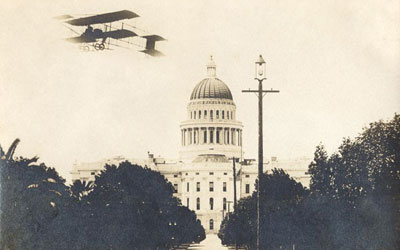 East side of the State Capitol showing the dome and entrance with an airplane flying overhead circa 1908